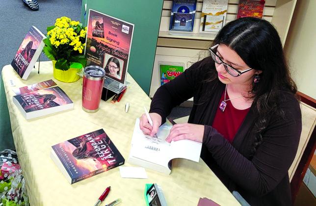 Angela Carlisle of DeMossville signs copies of her novel “Secondary Target,” which is set in Pendleton County, at at Logos Christian Bookstore in Alexandria. Photo courtesy of Angela Carlisle.